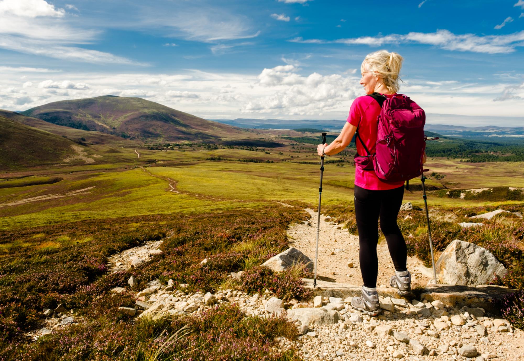 Woman stopping to admire the view on the trail in the Cairngorms National Park, Scotland.