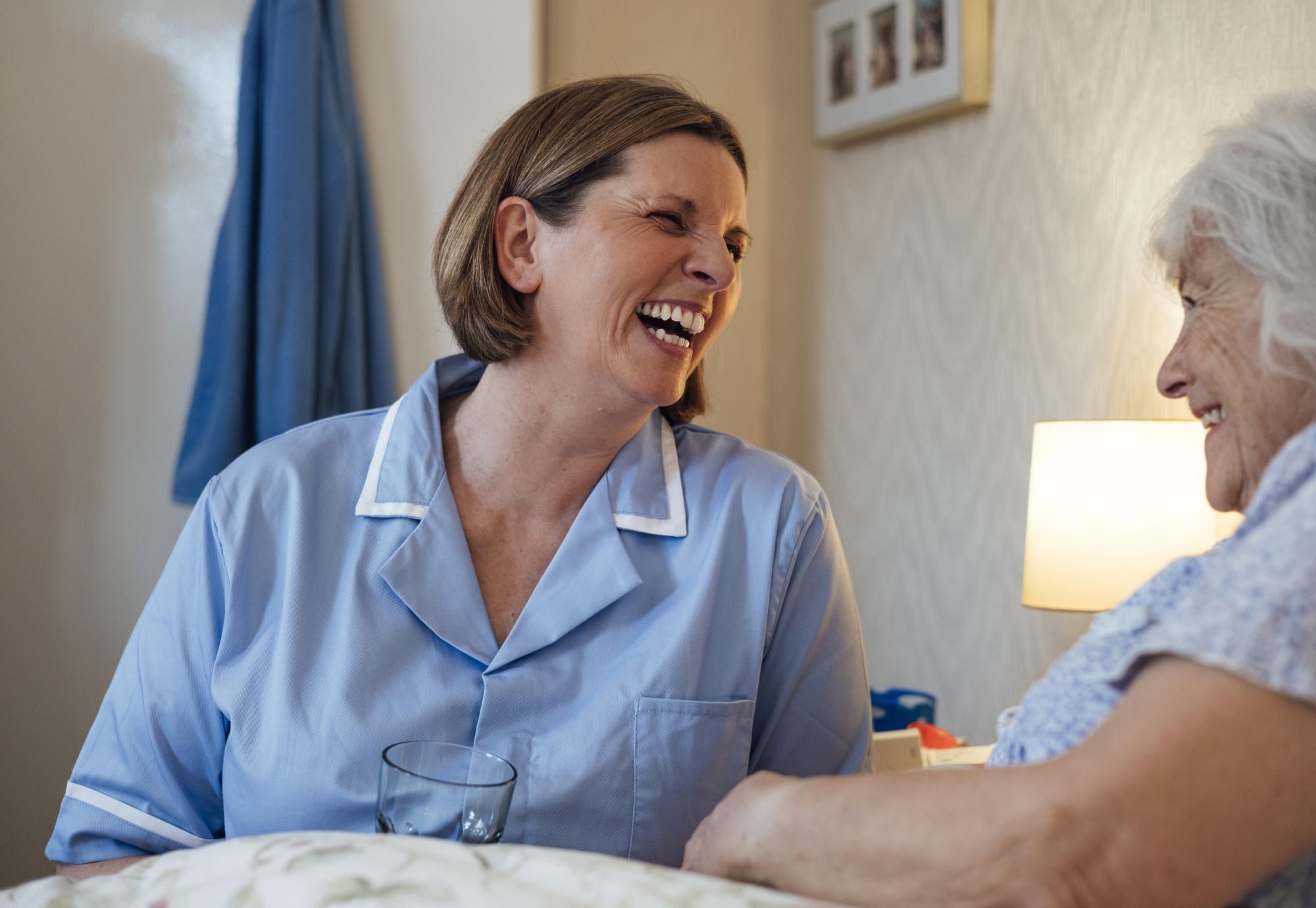 Nurse sat next to an older woman's bed