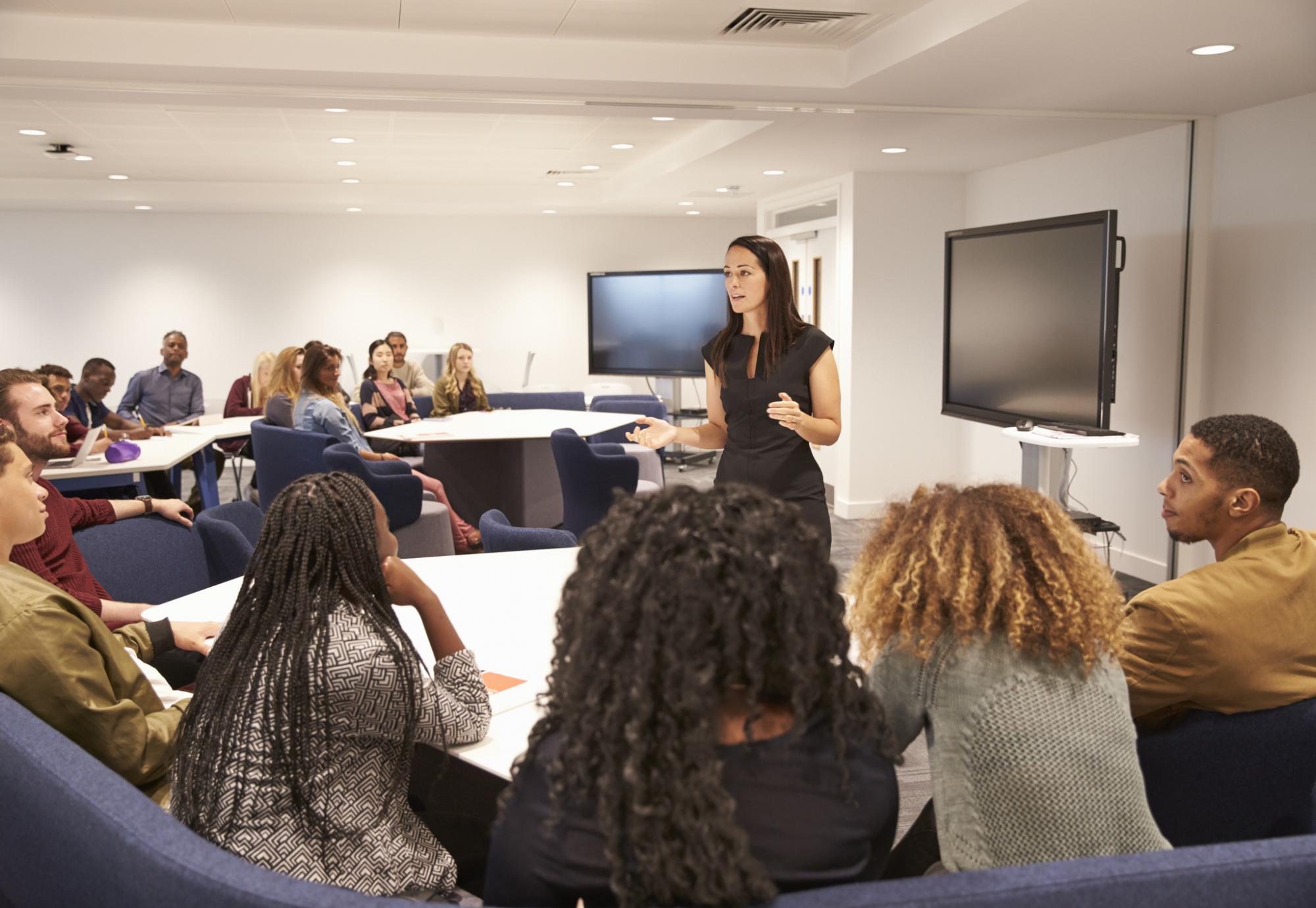 Female teacher addressing college students in a classroom