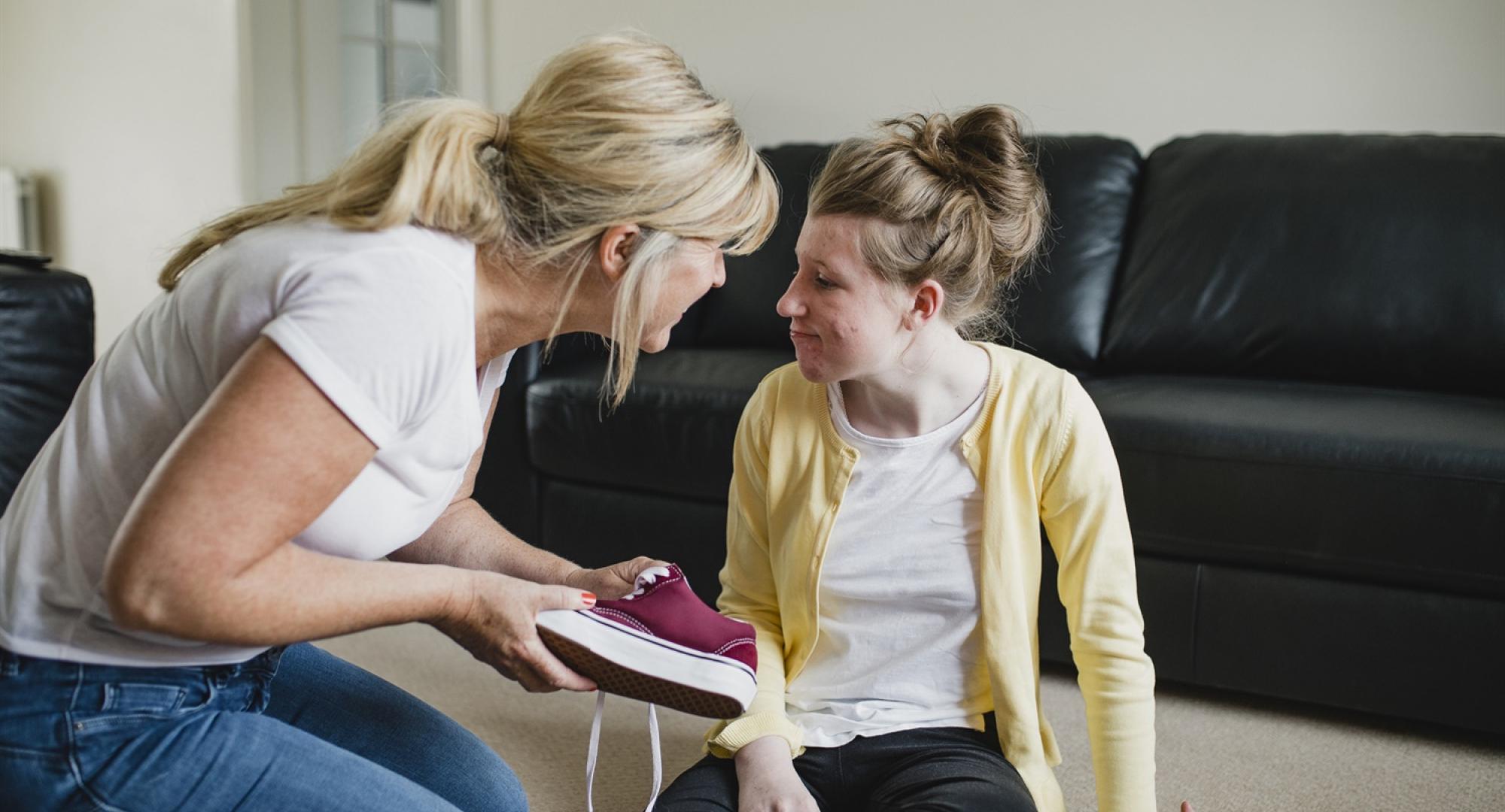 Carer helping girl with her shoes 