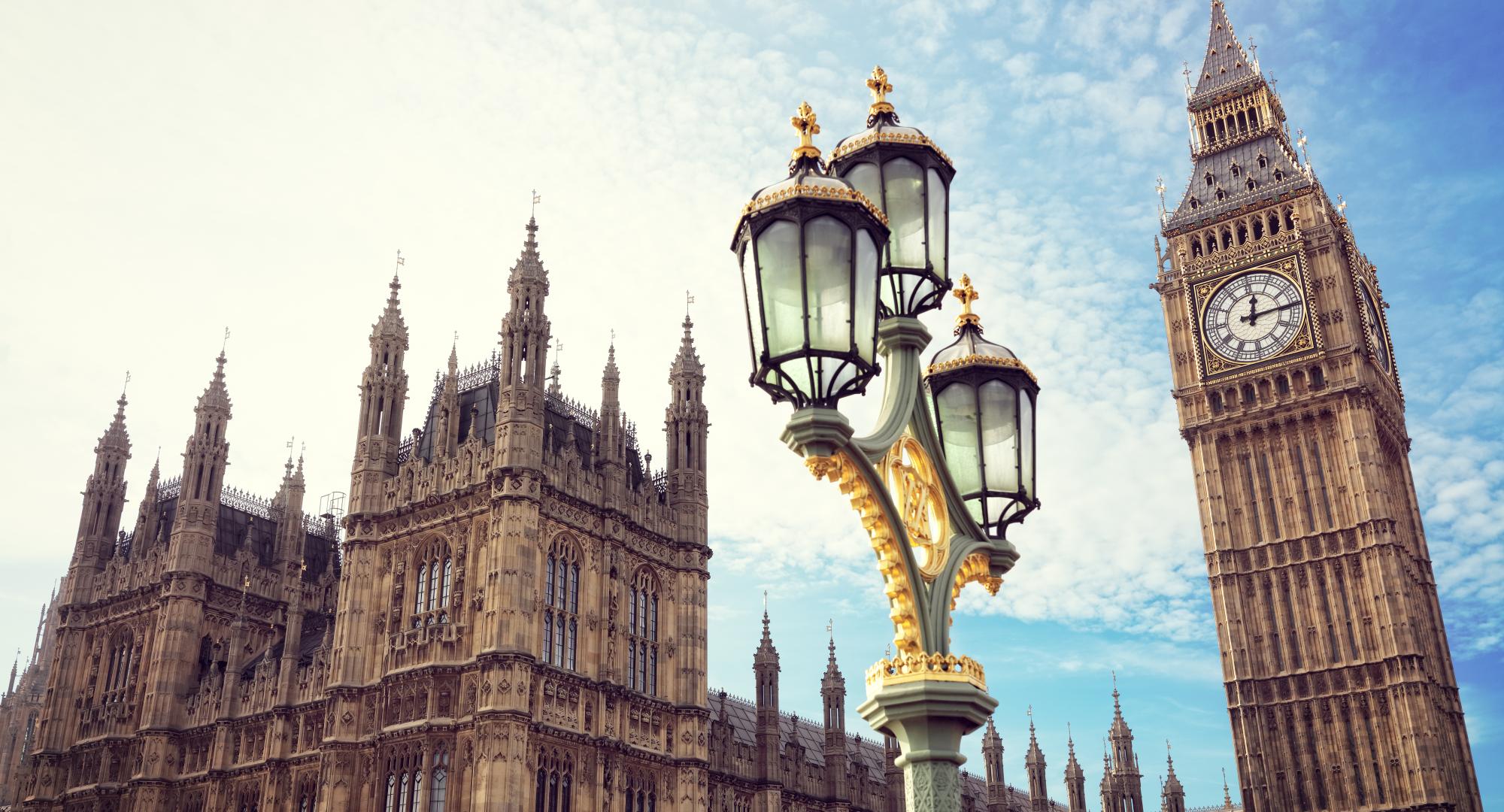 Big Ben in London with the houses of parliament and ornate street lamp.