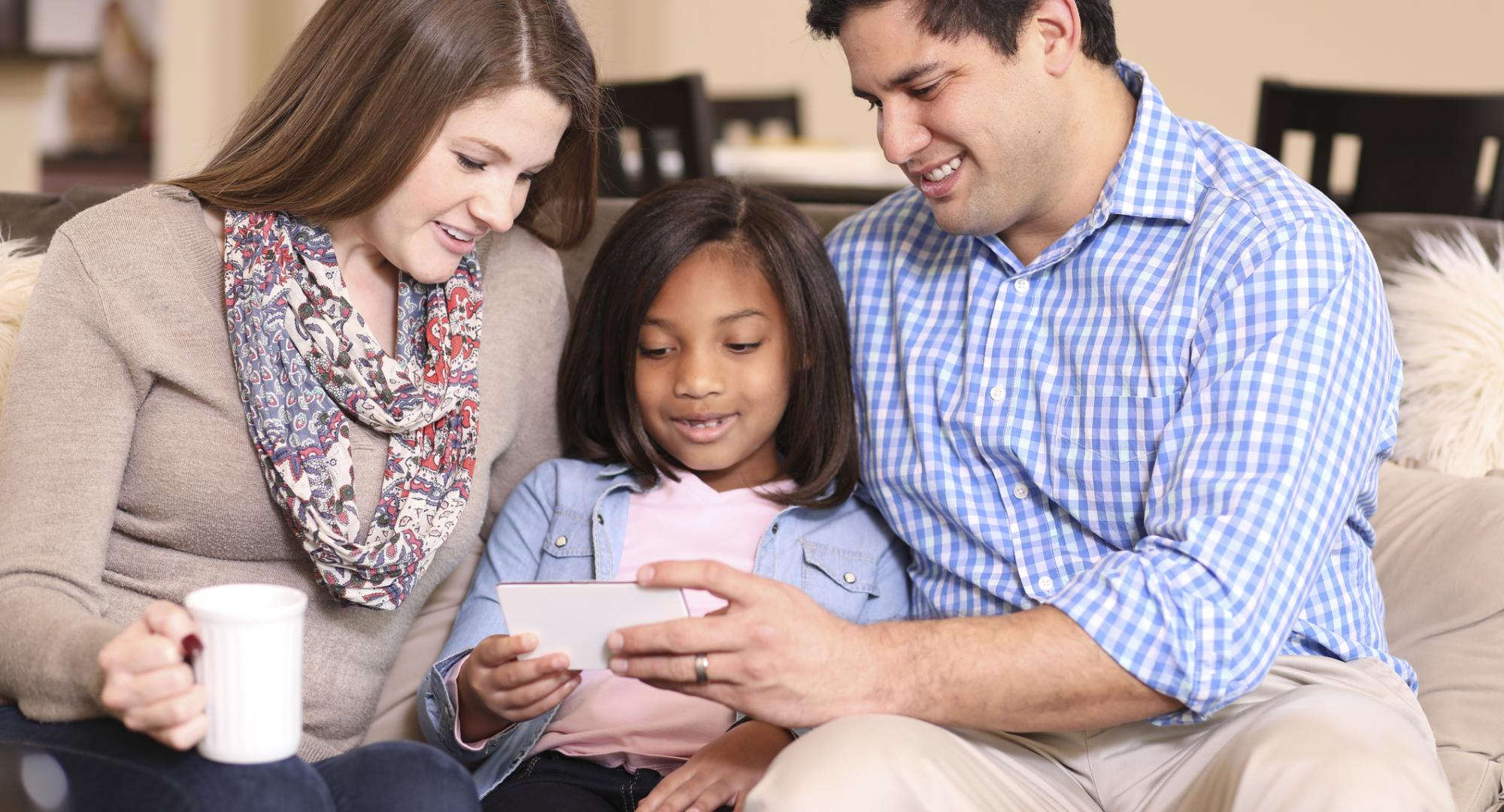 Adopted child sits with parents who are of a different race.