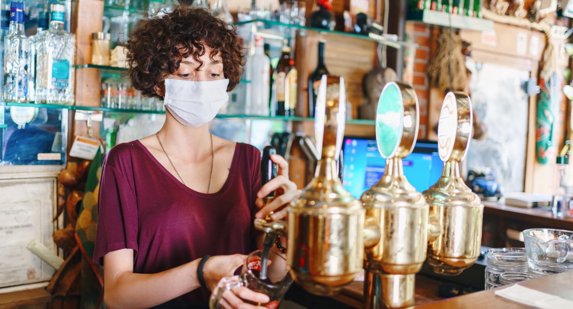 Woman with face mask pulls a pint