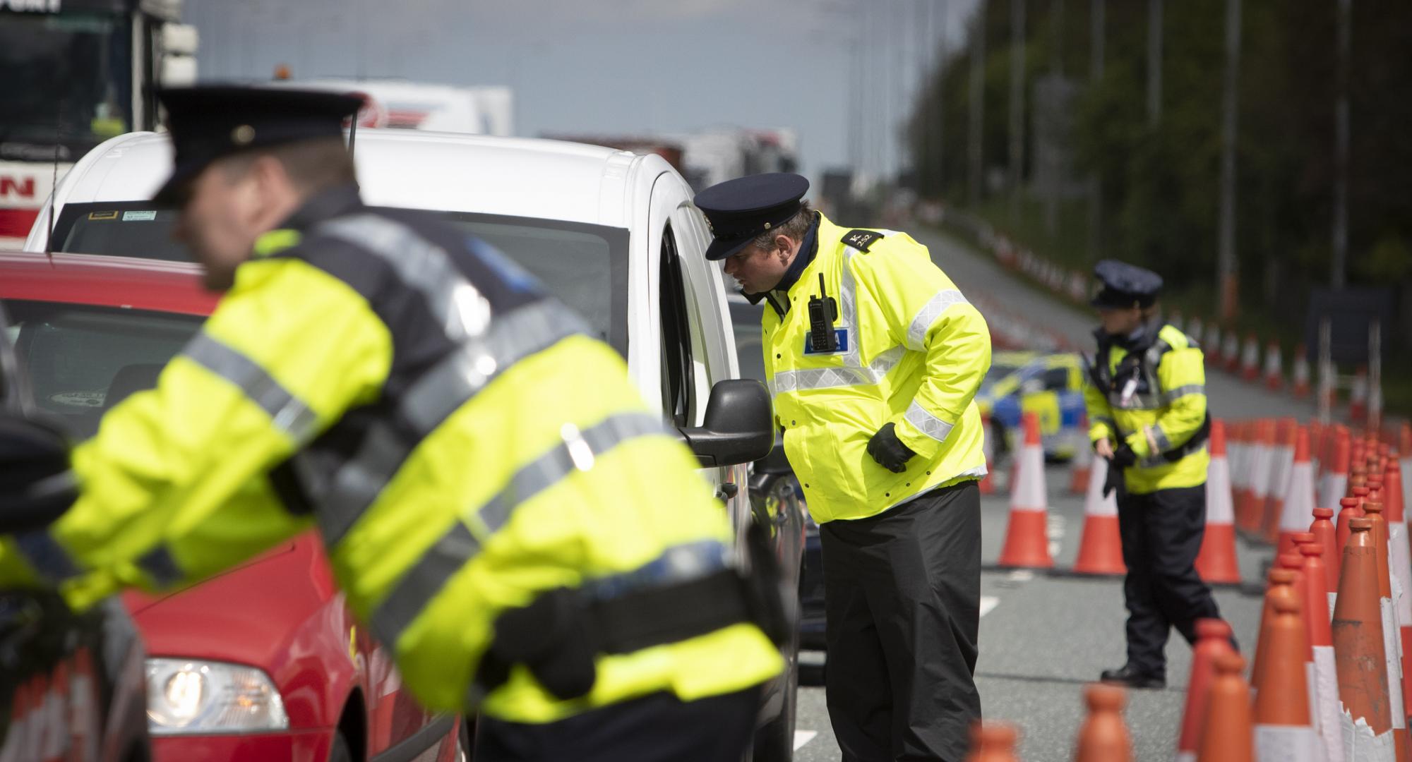 Police officers checking cars through the window. 