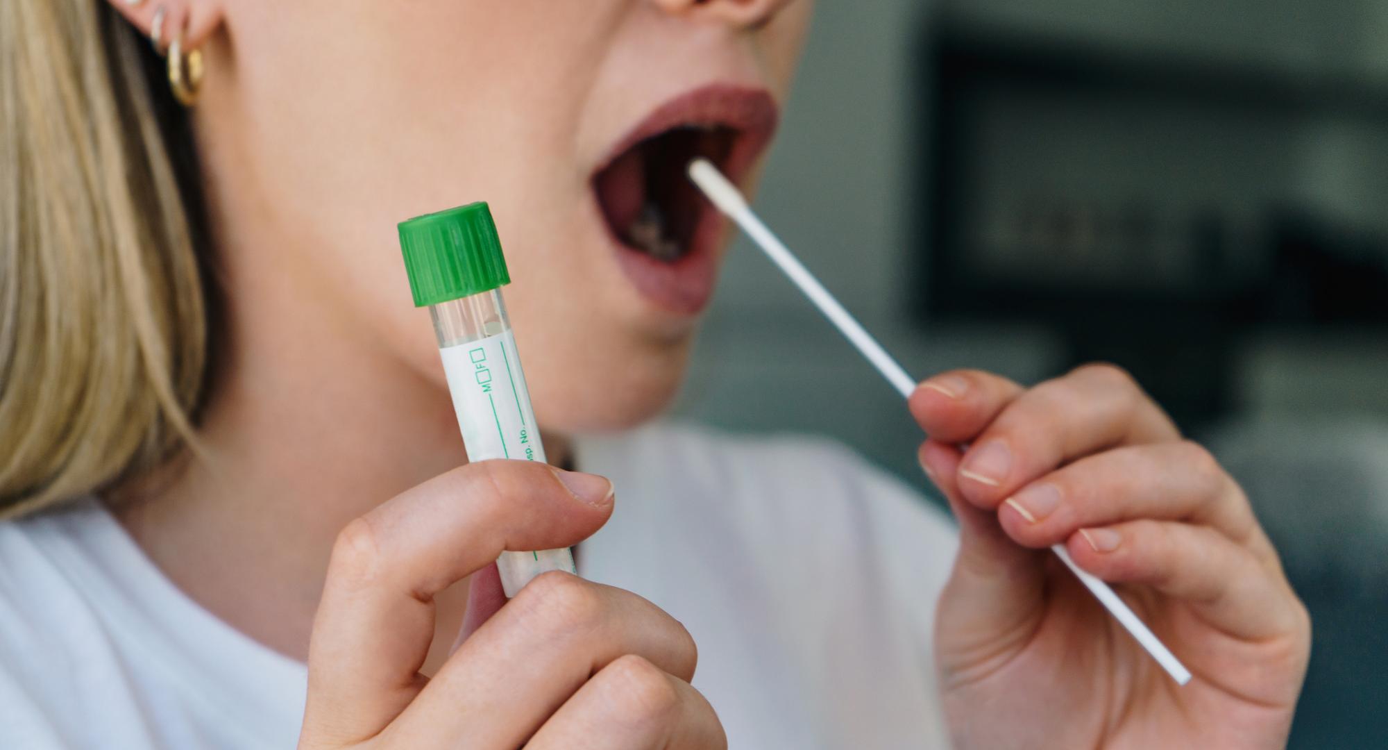 Woman inserts Covid-19 test into her mouth. 