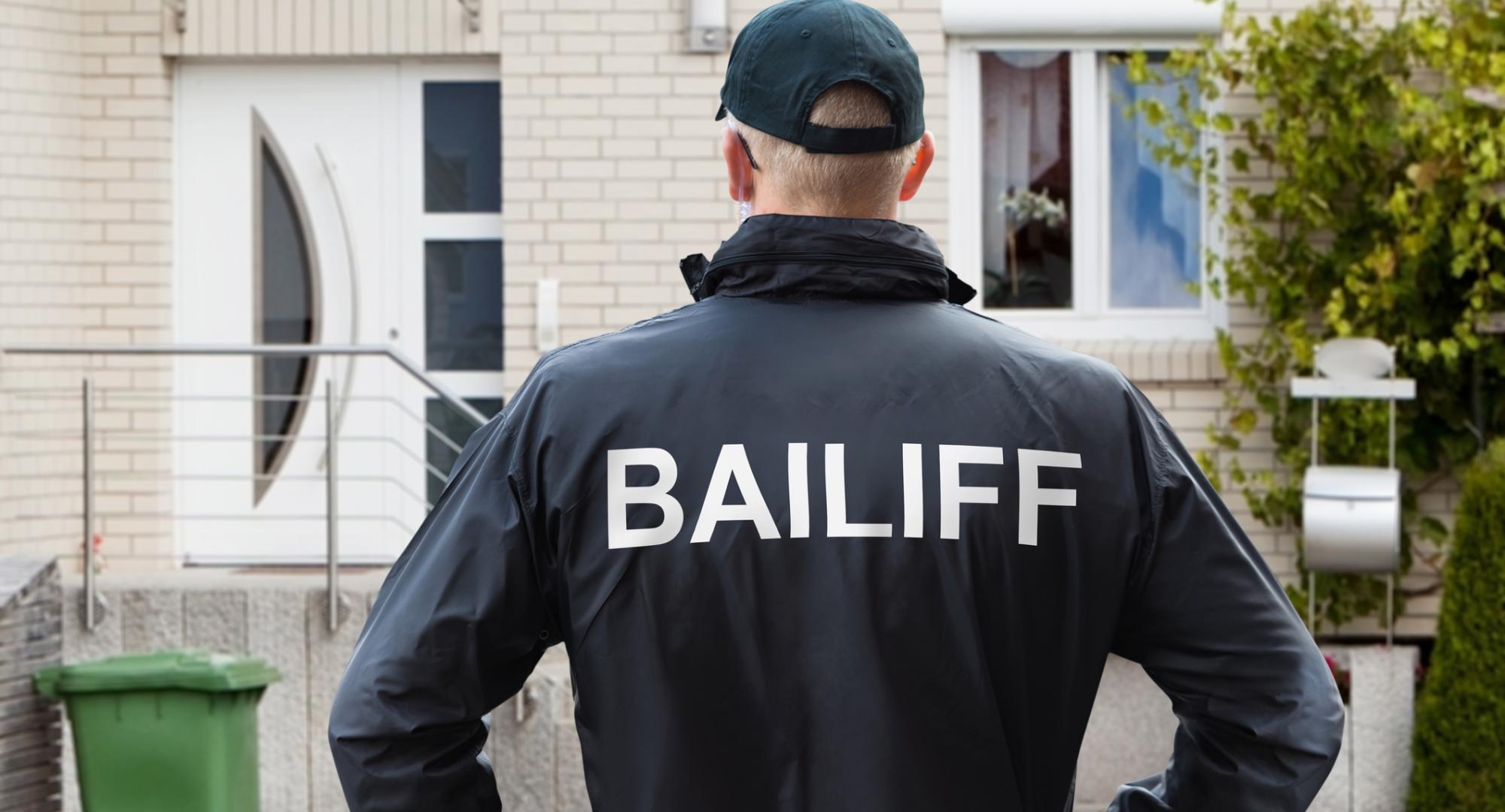 Bailiff stands in front of house ready to knock. 