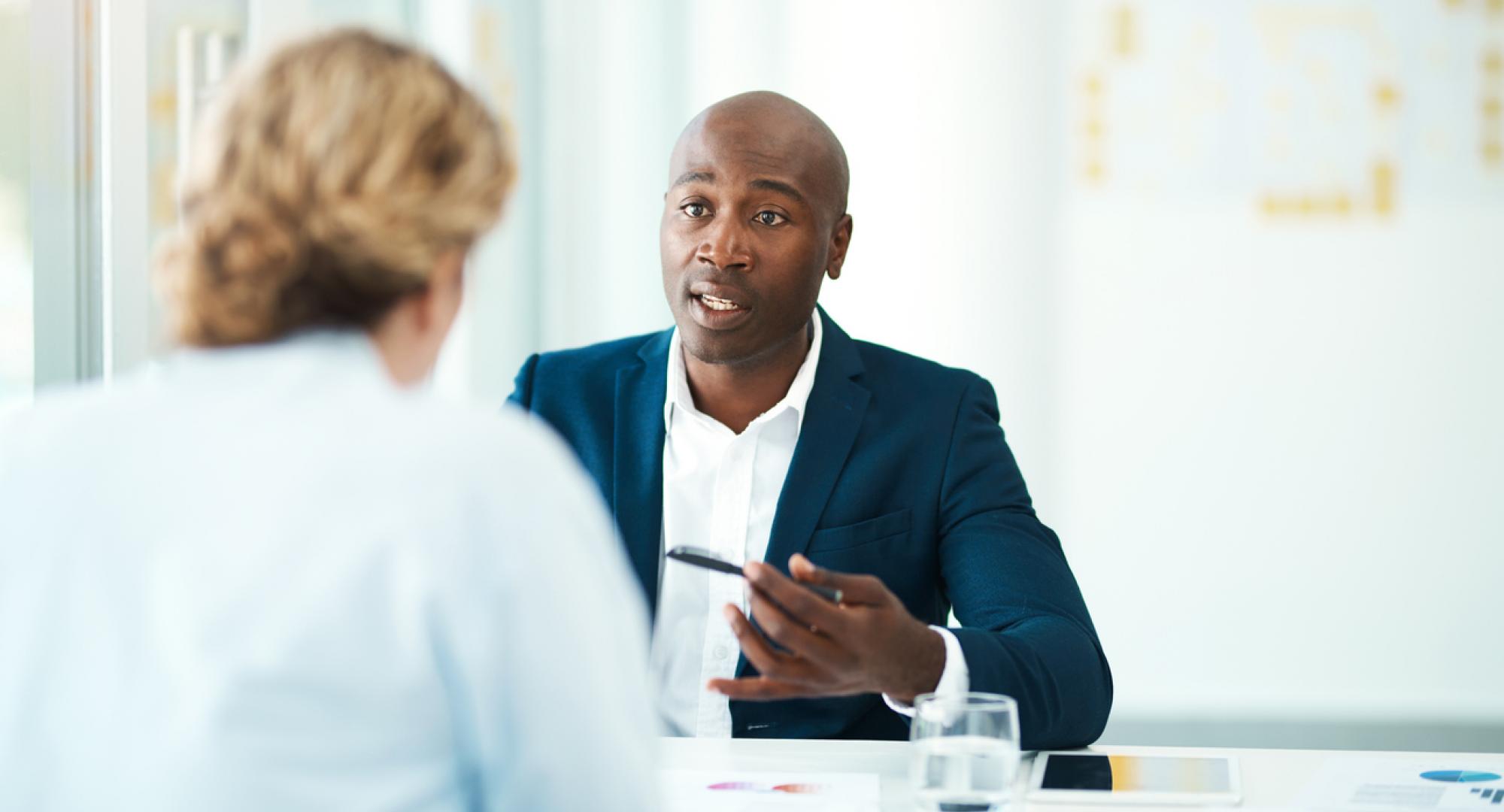 Man gives legal advice to woman in his office. 