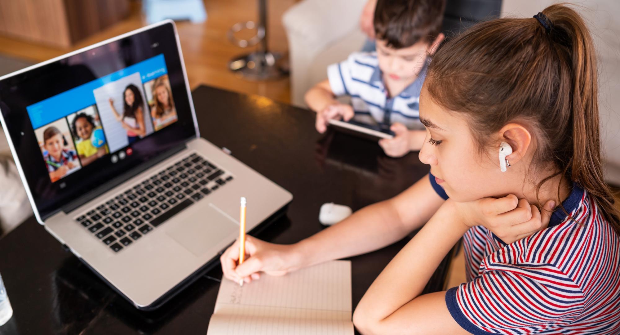 Children sit at laptop e-learning. 