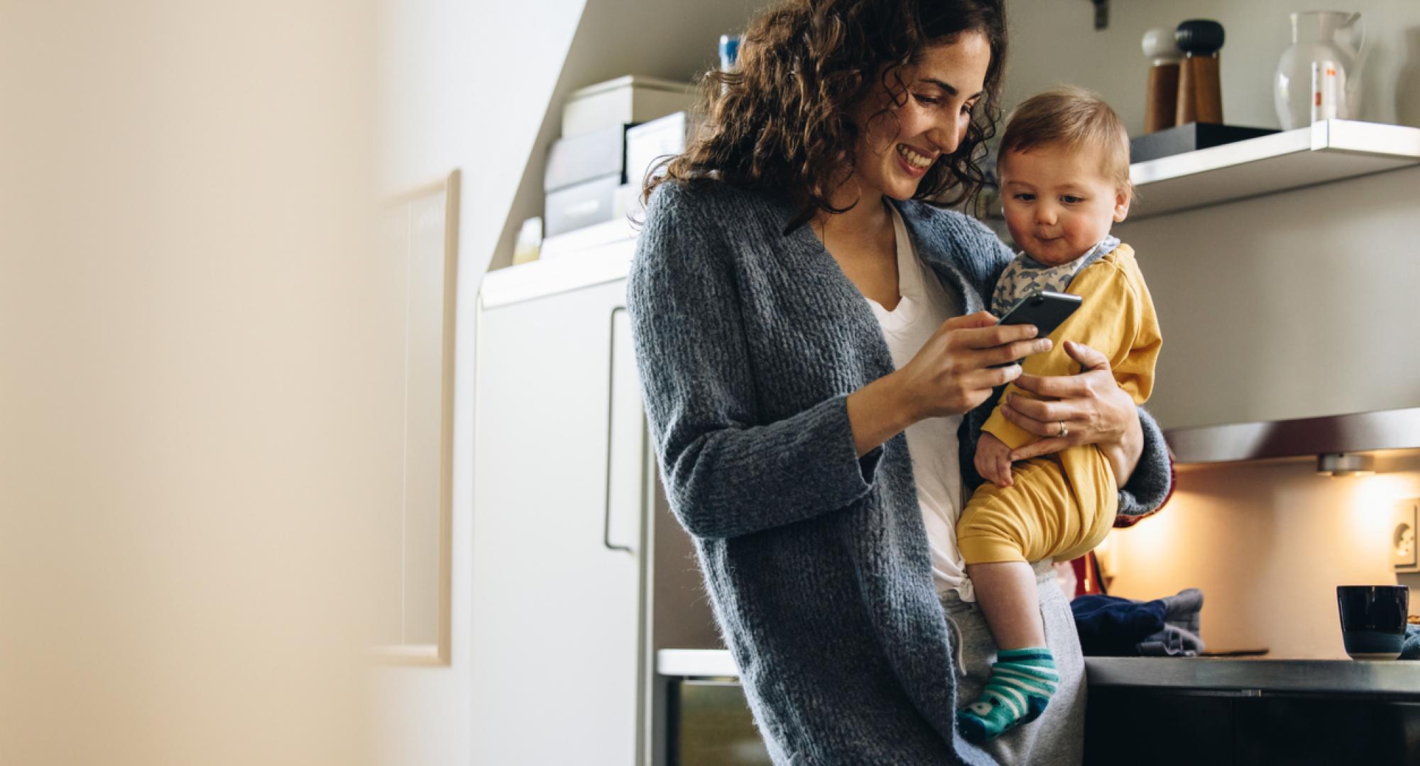 A mother holding a baby and a phone