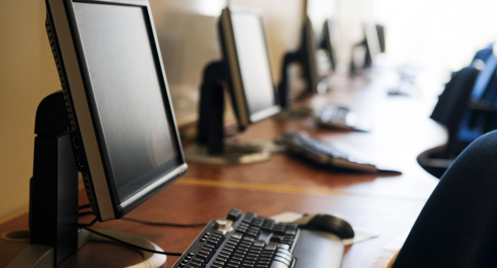 Row of modern screens and keyboards in a computer lab