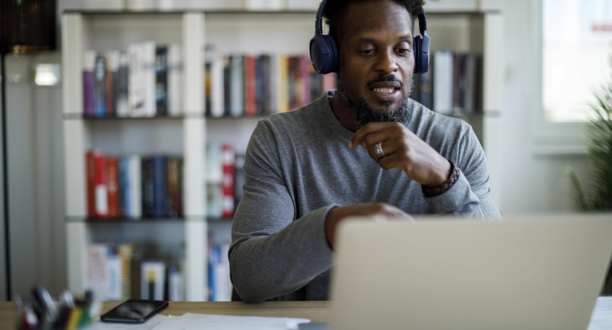 Man with headphones attends an online course at home