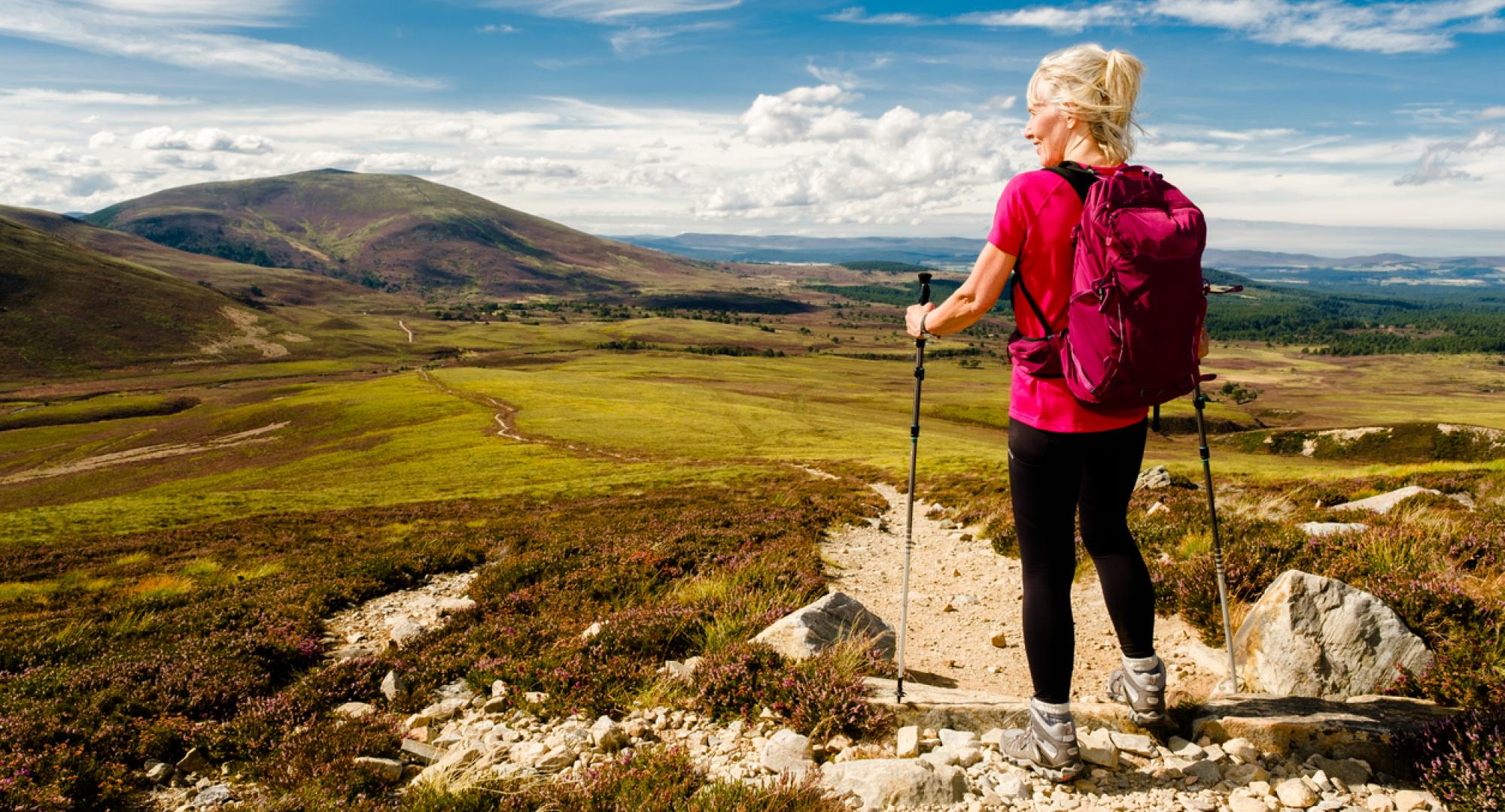 Woman stopping to admire the view on the trail in the Cairngorms National Park, Scotland.