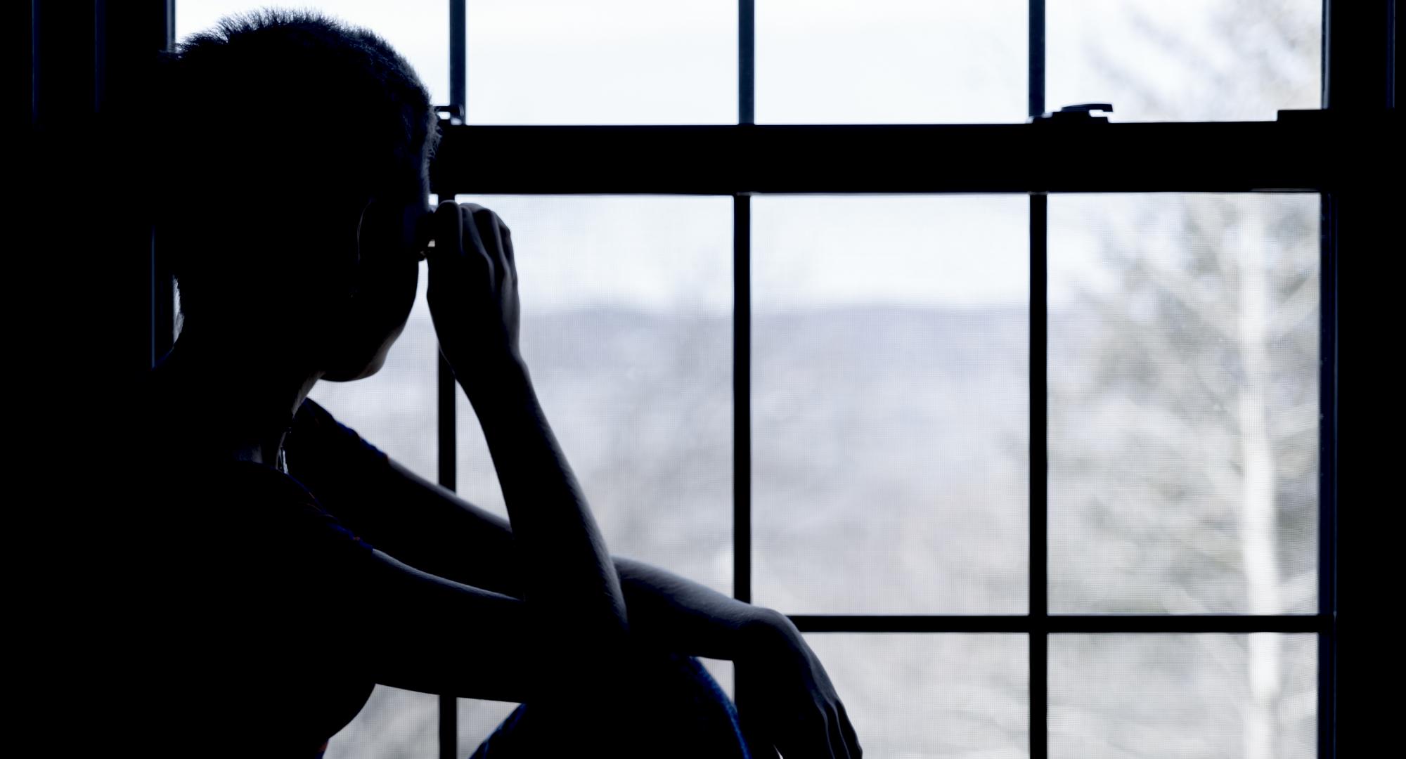 Teenage girl looking out of a hostel window