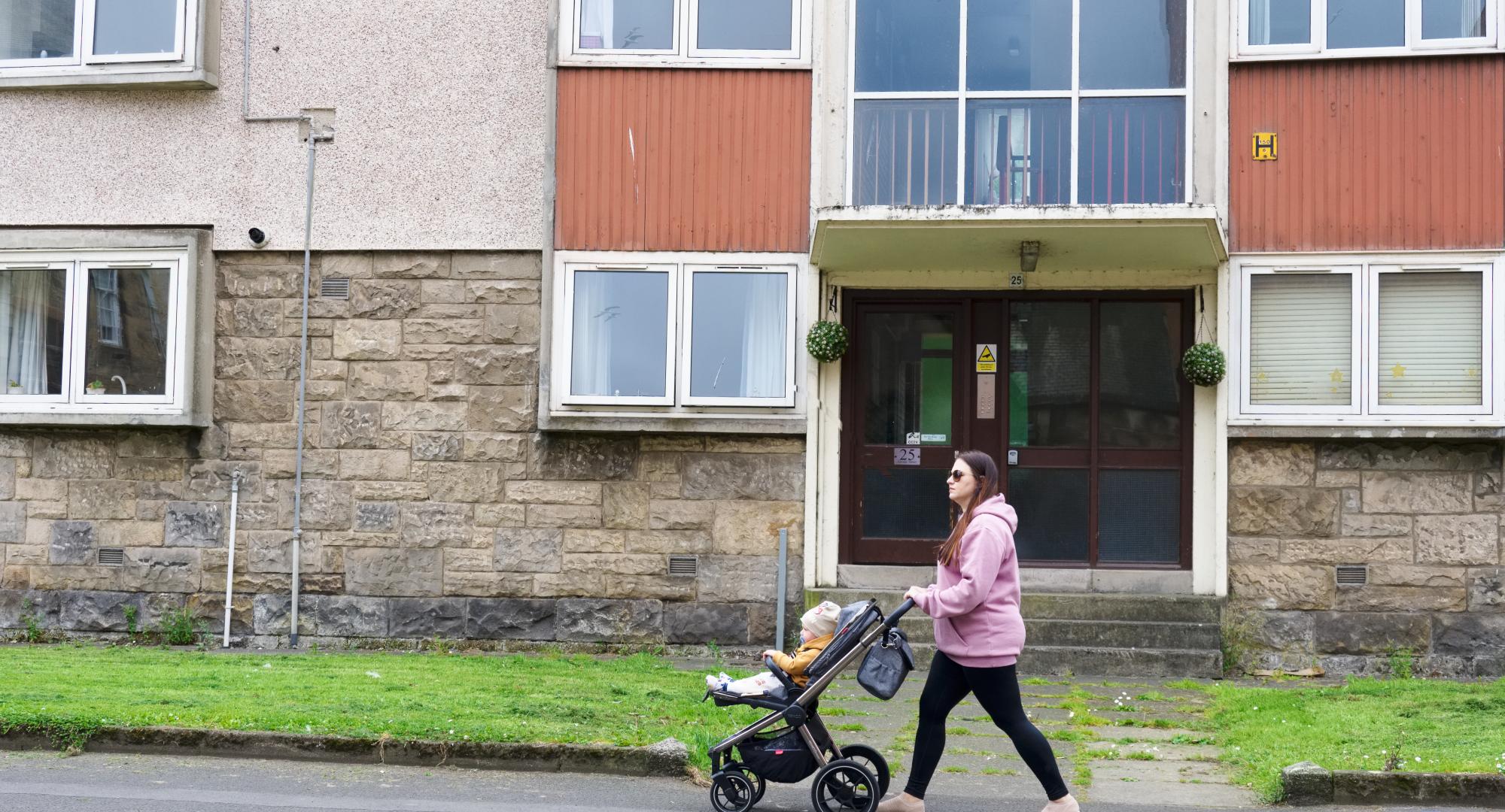 Mother and baby walking through a council estate