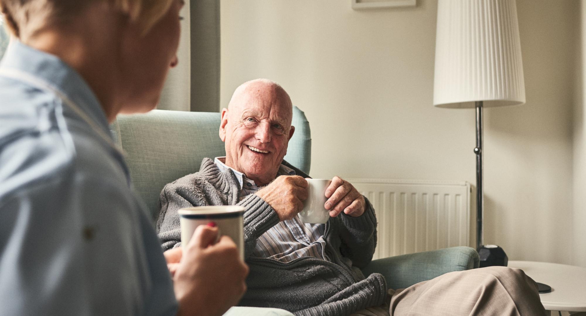 Smiling senior man talking to female caregiver