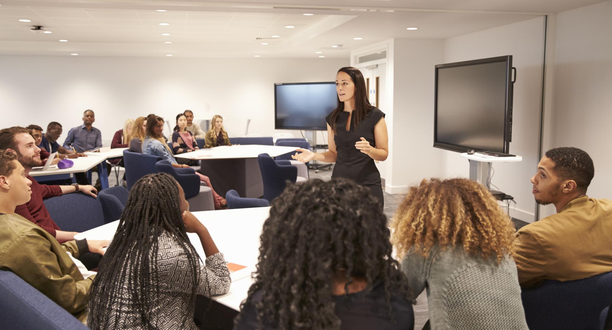 Female teacher addressing college students in a classroom