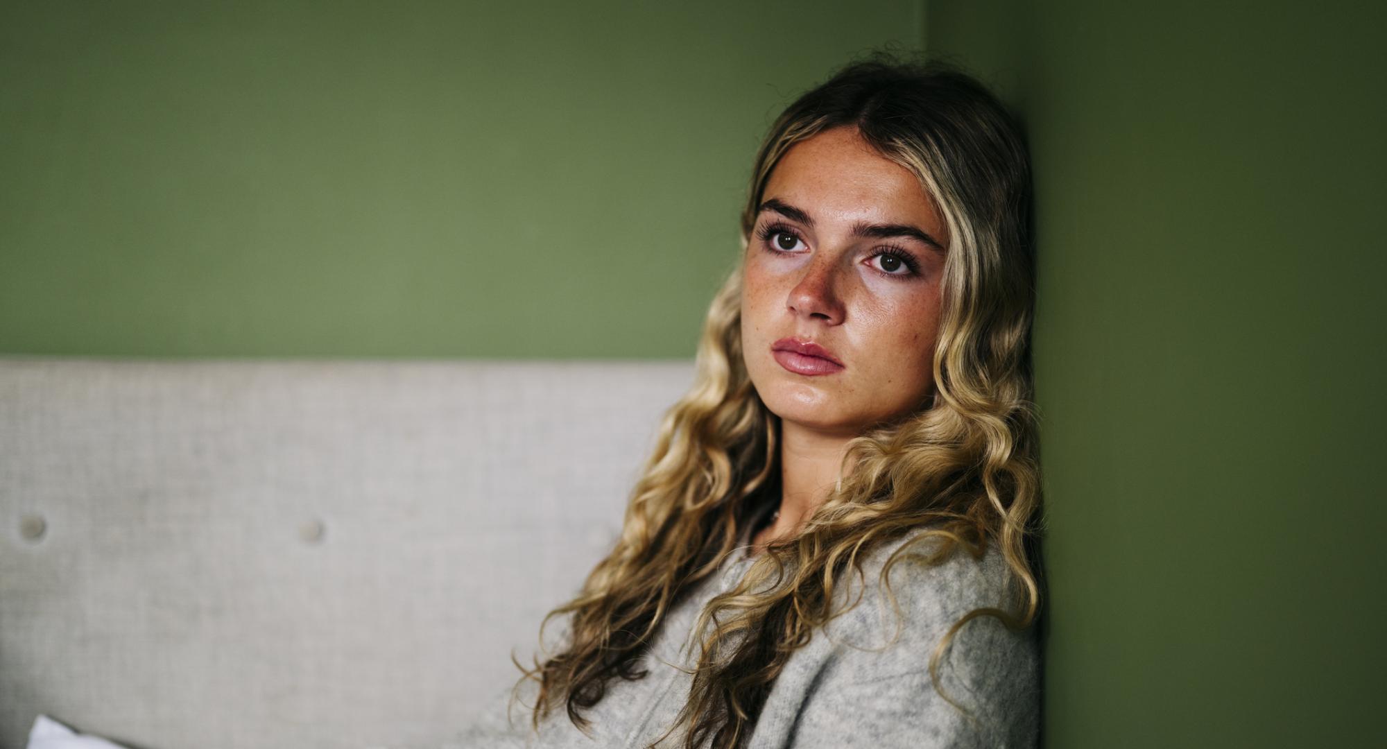 A teenage girl sat on the floor looking upset