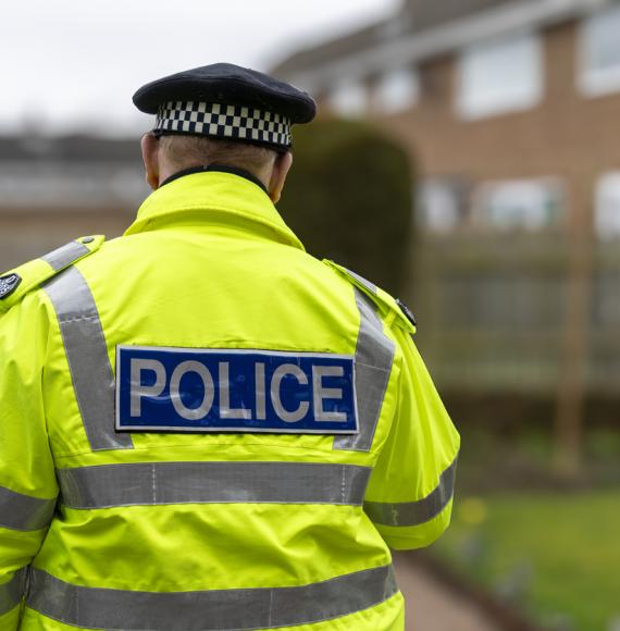 A policeman walking away from an elderly person's home.