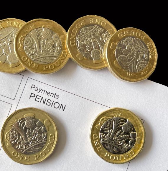 pound coins on top of an anonymous pension payment slip