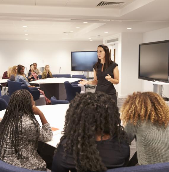 Female teacher addressing college students in a classroom